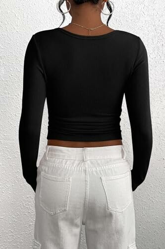 Person wearing a black long-sleeve top and white jeans, seen from the back.