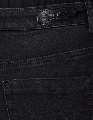 Close-up of black denim jeans with a visible brand label.