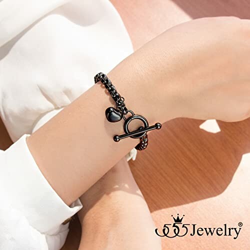 Person wearing a black heart bracelet with toggle clasp.