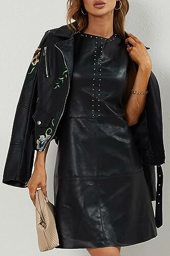 Woman wearing black leather dress with studded details and floral embroidered leather jacket.