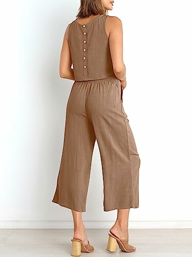 Woman wearing a brown sleeveless jumpsuit with buttoned back.