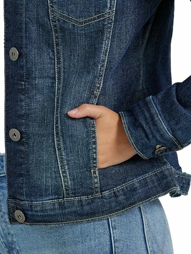 Closeup of a person wearing a denim jacket with hand in pocket.
