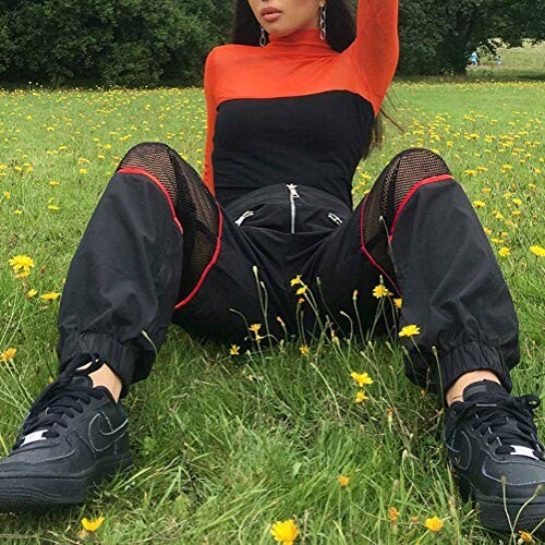 Person sitting on grass wearing black and orange outfit with sneakers.