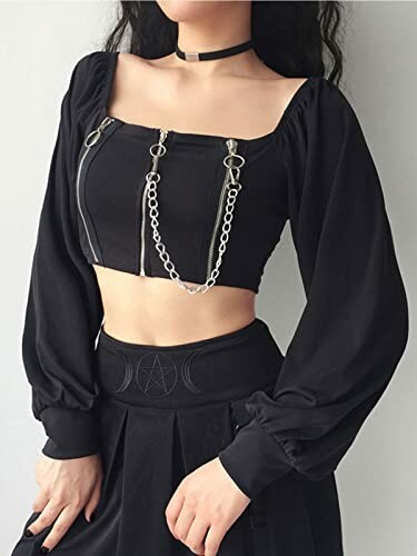 Person wearing a black gothic crop top with chain detail and long sleeves.