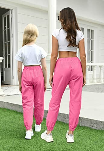 Two people in matching pink pants facing a building.