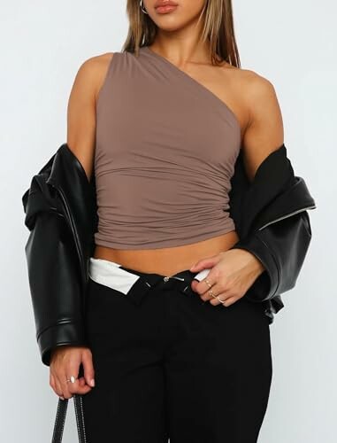 Woman wearing a one-shoulder top with a leather jacket.