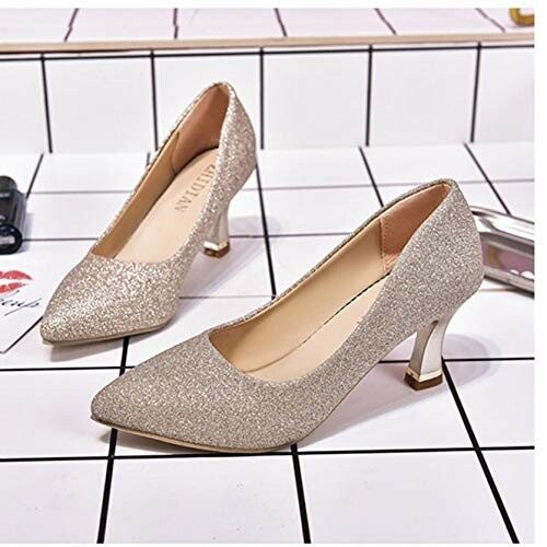 Pair of sparkly gold high heels on tile surface