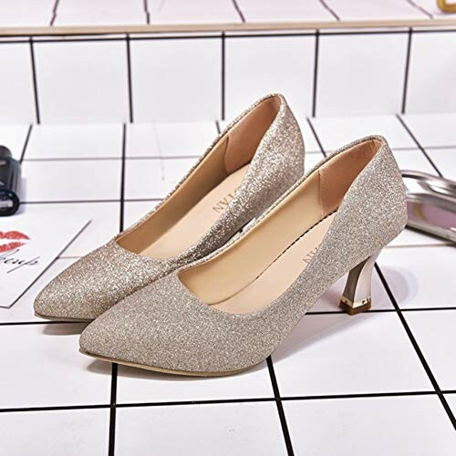 Pair of sparkly gold high heels on tiled surface.