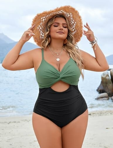 Woman in a green and black swimsuit with a straw hat on a beach