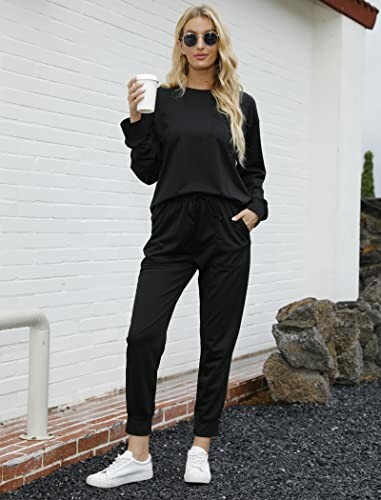 Woman in black tracksuit holding a coffee cup