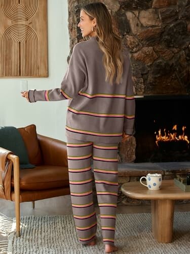 Woman in striped pajamas standing by a fireplace