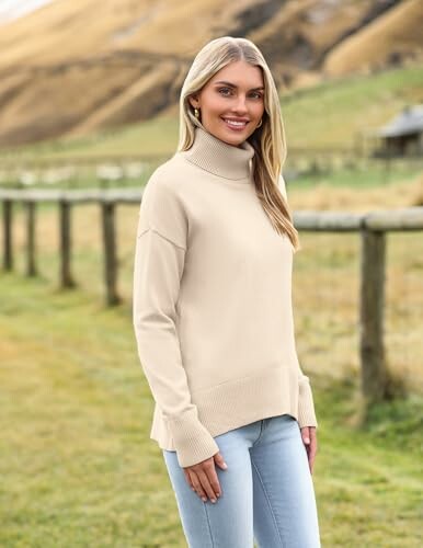 Woman wearing a beige sweater standing outside.