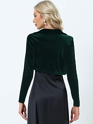 Woman wearing a green velvet jacket over a black dress