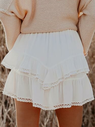 Woman wearing a beige sweater and white layered skirt