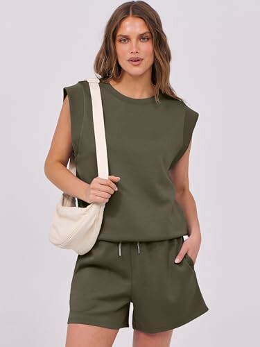Woman in olive sleeveless top and shorts with a white bag.