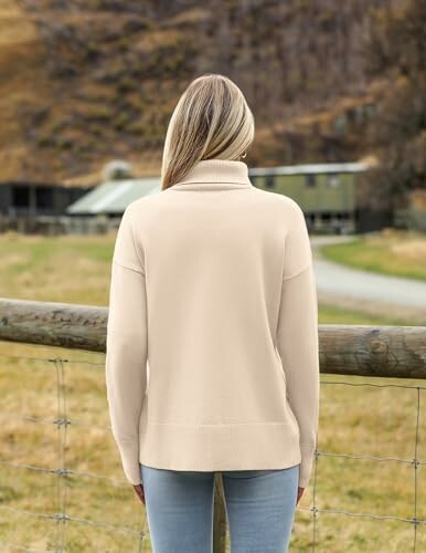 Woman in cream sweater standing outdoors with a rural background