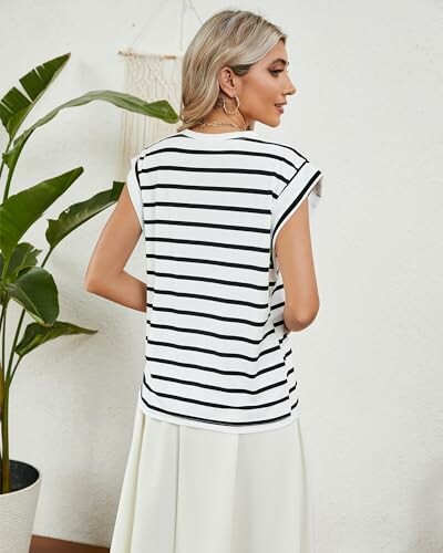 Woman in a striped shirt facing away next to a plant.