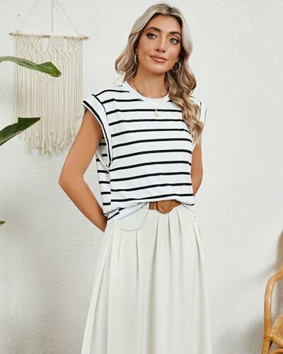 Woman in striped shirt and white skirt posing indoors.