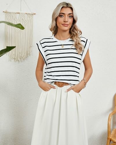 Woman wearing a striped shirt and white skirt standing indoors.