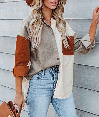 Woman in a colorblock shirt and jeans holding a bag