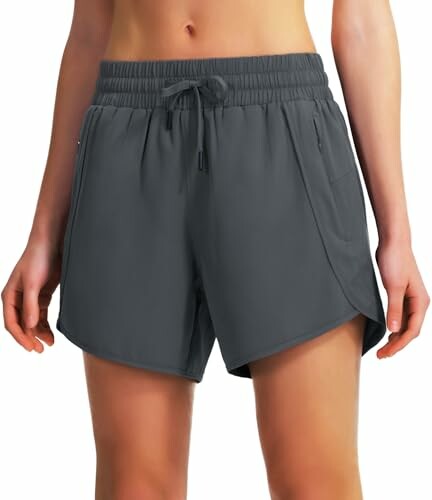 Woman wearing dark gray sports shorts with pockets.