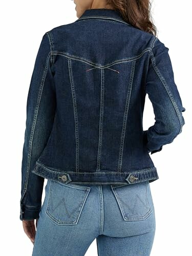 Woman wearing a denim jacket and jeans, viewed from the back.